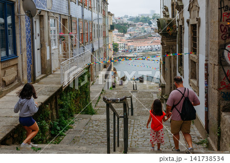Family Walking Down Historic Cobblestone Street Toward Ribeira District in Porto Portugal 141738534