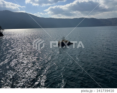 青森県十和田市の湖、十和田湖の遊覧船から見た小さな浮島と湖の風景です。 青森県十和田市の湖、十和田湖の遊覧船から見た小さな浮島と湖の風景です。 141739410