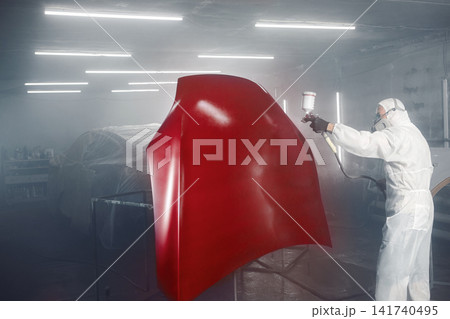 Professional car painter in chamber paints automobile bonnet. Professional car painter in chamber paints automobile bonnet. 141740495