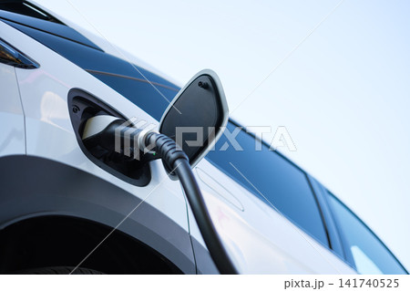 Electric car charging at a outdoor public charging station. Electric car charging at a outdoor public charging station. 141740525