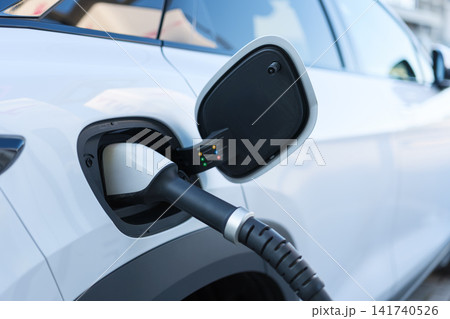 Electric car charging at a outdoor public charging station. Electric car charging at a outdoor public charging station. 141740526