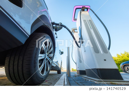 Electric car charging at a outdoor public charging station. Electric car charging at a outdoor public charging station. 141740529