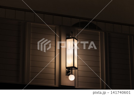 A warm interior wall lantern lamp casts a soft ambient glow across a modern architecture A warm interior wall lantern lamp casts a soft ambient glow across a modern architecture 141740601
