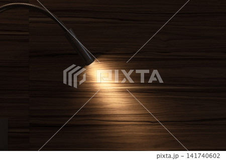 A flexible reading lamp casts a warm, focused glow across a dark wood surface A flexible reading lamp casts a warm, focused glow across a dark wood surface 141740602