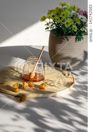 Glass Honey Jar and Dipper on a Wooden Board Glass Honey Jar and Dipper on a Wooden Board 141742083
