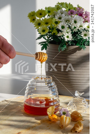 Drizzling Honey from a Dipper into a Beehive Jar Drizzling Honey from a Dipper into a Beehive Jar 141742087