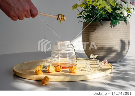 Drizzling Golden Honey into a Jar by Flowers Drizzling Golden Honey into a Jar by Flowers 141742091