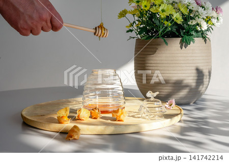 Hand Pouring Honey into a Beehive Shaped Jar Hand Pouring Honey into a Beehive Shaped Jar 141742214