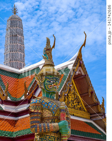 Colorful giant guardian statue at Wat Phra Kaew with traditional Thai temple architecture in Bangkok. Colorful giant guardian statue at Wat Phra Kaew with traditional Thai temple architecture in Bangkok. 141742686