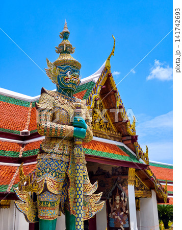 Colorful giant guardian statue at Wat Phra Kaew with traditional Thai temple architecture in Bangkok. Colorful giant guardian statue at Wat Phra Kaew with traditional Thai temple architecture in Bangkok. 141742693