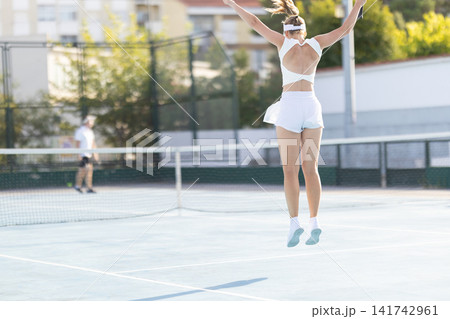Woman jumps during a tennis match on a sunny day at a local court Woman jumps during a tennis match on a sunny day at a local court 141742961