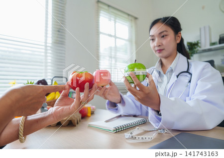 Asian female nutritionist consulting patient about healthy diet and fruit nutrition in clinic 141743163
