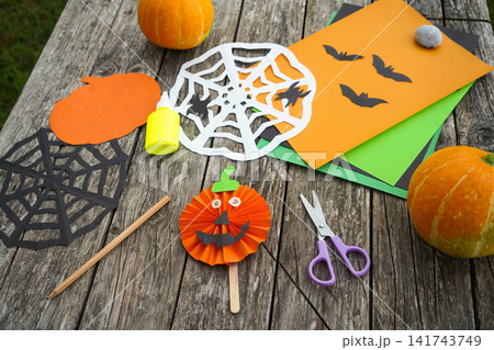 High angle shot of handmade paper pumpkin jack-o'-lantern, spiderwebs and bats arranged on a rustic wooden table High angle shot of handmade paper pumpkin jack-o'-lantern, spiderwebs and bats arranged on a rustic wooden table 141743749