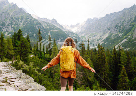 Smiling traveler with a bright backpack on a hiking mountain trail. Active lifestyle. Smiling traveler with a bright backpack on a hiking mountain trail. Active lifestyle. 141744298