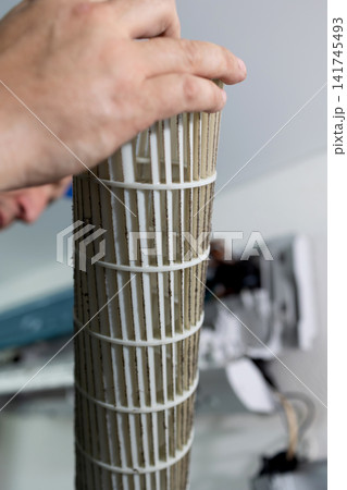 Technician cleaning dirty air conditioner blower fan. Maintenance of home cooling system unit. Technician cleaning dirty air conditioner blower fan. Maintenance of home cooling system unit. 141745493