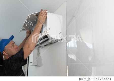 Technician cleaning wall air conditioner. Professional maintenance of split system in bright room. Technician cleaning wall air conditioner. Professional maintenance of split system in bright room. 141745524