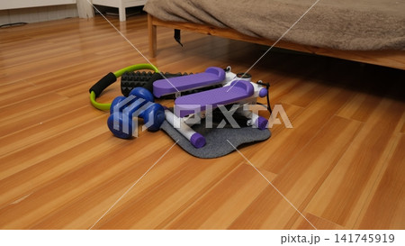 Compact home equipment set on a wooden floor. Stepper, dumbbells, foam roller, and Pilates ring. Small apartment workout. Home Gym Setup. Space-Saving Fitness. Weight Loss Programs. Self-Care Routine Compact home equipment set on a wooden floor. Stepper, dumbbells, foam roller, and Pilates ring. Small apartment workout. Home Gym Setup. Space-Saving Fitness. Weight Loss Programs. Self-Care Routine 141745919