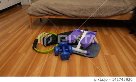 Compact home equipment set on a wooden floor. Stepper, dumbbells, foam roller, and Pilates ring. Small apartment workout. Home Gym Setup. Space-Saving Fitness. Weight Loss Programs. Self-Care Routine Compact home equipment set on a wooden floor. Stepper, dumbbells, foam roller, and Pilates ring. Small apartment workout. Home Gym Setup. Space-Saving Fitness. Weight Loss Programs. Self-Care Routine 141745920