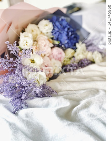 Beautiful bouquet of pastel flowers on bed in soft natural light cozy lifestyle scene Beautiful bouquet of pastel flowers on bed in soft natural light cozy lifestyle scene 141745960