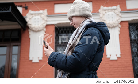 Teenage girl talking smartphone in blurry city park. Young teen female having phone call conversation. Gen Z Youth Communication. Authentic Everyday City Realities. Chilly Weather. Cozy Street Style Teenage girl talking smartphone in blurry city park. Young teen female having phone call conversation. Gen Z Youth Communication. Authentic Everyday City Realities. Chilly Weather. Cozy Street Style 141746002