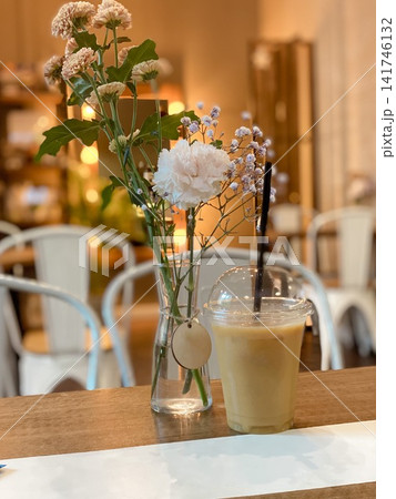 Cozy cafe scene with a glass of iced coffee and a small bouquet of flowers Cozy cafe scene with a glass of iced coffee and a small bouquet of flowers 141746132