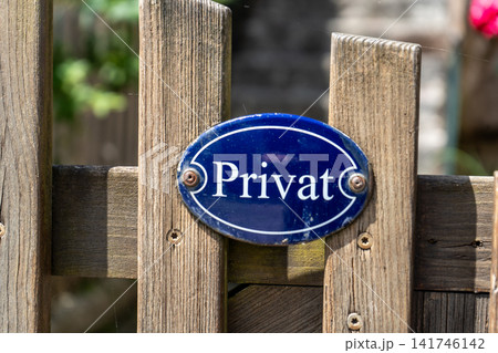 Blue metal Sign with a German Word Privat on a Wooden Fence Indicating Private Property Area Outdoors Blue metal Sign with a German Word Privat on a Wooden Fence Indicating Private Property Area Outdoors 141746142