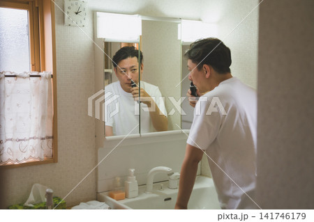 洗面台の鏡に映る自分を見ながら鼻毛を整える40代男性のノーズトリミング 洗面台の鏡に映る自分を見ながら鼻毛を整える40代男性のノーズトリミング 141746179