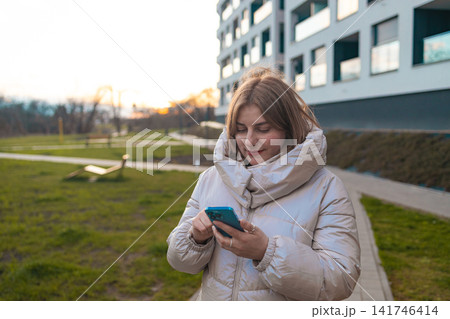 happy woman smiling and looking at the camera in a grassy outdoor area with a modern building in the background, commercial lifestyle fashion scene, green and white. happy woman smiling and looking at the camera in a grassy outdoor area with a modern building in the background, commercial lifestyle fashion scene, green and white. 141746414