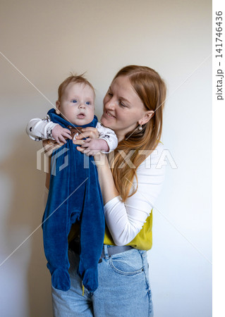 Happy young mother holding her cute baby boy on a light background. 141746436