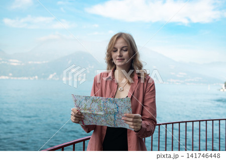 Young woman tourist holding a paper map at Lake Como Young woman tourist holding a paper map at Lake Como 141746448
