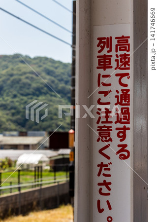 駅ホームの警告表示「高速で通過する列車にご注意ください」(背景に広がる田園風景) 駅ホームの警告表示「高速で通過する列車にご注意ください」(背景に広がる田園風景) 141746669