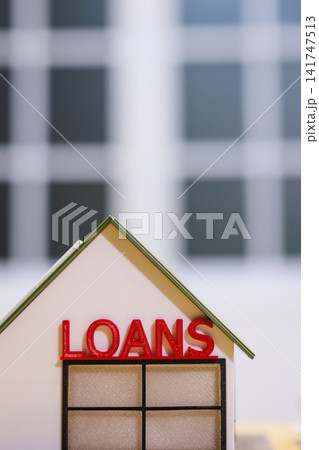 Small model house with the word loans on the roof, with a blurred building background Small model house with the word loans on the roof, with a blurred building background 141747513