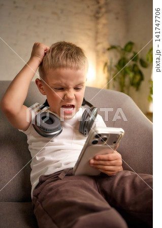 Frustrated five-year-old boy reacting emotionally to smartphone content. 141747706