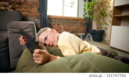 Five-year-old boy lying on sofa and watching digital content on tablet at home Five-year-old boy lying on sofa and watching digital content on tablet at home 141747768