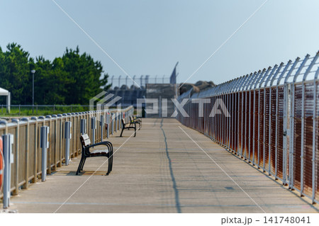 夏の爽やかな青空と日差しが降り注ぐ海辺の散策路と並ぶベンチ 夏の爽やかな青空と日差しが降り注ぐ海辺の散策路と並ぶベンチ 141748041