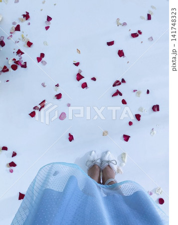 Woman in dress standing on white floor with petals, soft light, romantic aesthetic 141748323