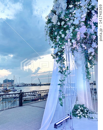 Wedding arch with flowers near marina at sunset, soft light, romantic atmosphere Wedding arch with flowers near marina at sunset, soft light, romantic atmosphere 141748369