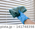 Hand in Glove Cleaning White Window Blinds with Microfiber Cloth 141748398