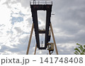 Low Angle View of Industrial Gantry Crane Steel Structure Against Cloudy Sky 141748408