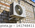 Side View of Outdoor Air Conditioning Unit Mounted on Brick Building Wall 141748411