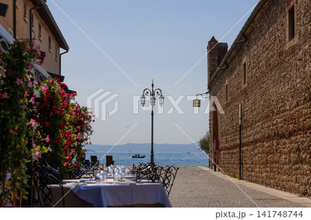 Restaurant street in Lazise beside an old stone wall with a view to Lake Garda Restaurant street in Lazise beside an old stone wall with a view to Lake Garda 141748744