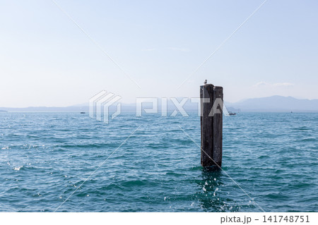 Solitary mooring post in open blue Lake Garda water near Lazise in summer daylight Solitary mooring post in open blue Lake Garda water near Lazise in summer daylight 141748751