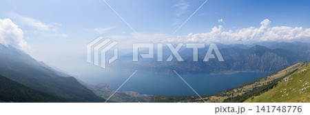 Monte Baldo view across an ultra-wide Lake Garda panorama in soft summer haze Monte Baldo view across an ultra-wide Lake Garda panorama in soft summer haze 141748776