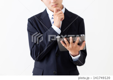 タブレットを持って悩むスーツを着た若い男性ビジネスマン 141749120
