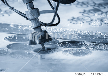 Multi axis abrasive waterjet cutting machine cutting aluminum plate in light blue lighting Multi axis abrasive waterjet cutting machine cutting aluminum plate in light blue lighting 141749250