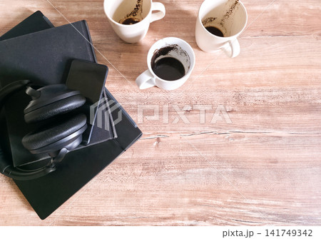 Three empty coffee cups beside a closed laptop, notebook and headphones on a wooden desk with copy space. Concept of finished workday, productivity and burnout. Three empty coffee cups beside a closed laptop, notebook and headphones on a wooden desk with copy space. Concept of finished workday, productivity and burnout. 141749342