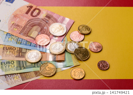 Spain, Spanish euro cash and cent coins against the background of the flag. Euro cash Spain, Spanish euro cash and cent coins against the background of the flag. Euro cash 141749421