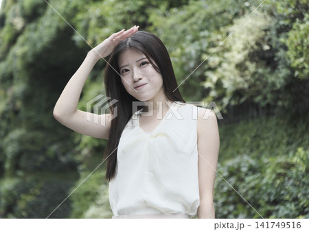 緑豊かな公園で微笑むノースリーブの若い女性 緑豊かな公園で微笑むノースリーブの若い女性 141749516