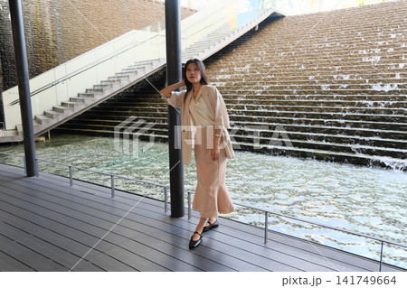 都心の水辺の広場で微笑むオフィスカジュアル姿の若い女性 都心の水辺の広場で微笑むオフィスカジュアル姿の若い女性 141749664