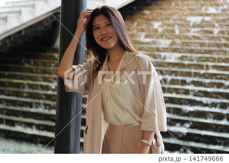 都心の水辺の広場で微笑むオフィスカジュアル姿の若い女性 都心の水辺の広場で微笑むオフィスカジュアル姿の若い女性 141749666